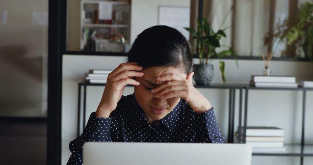 Kvinde ved computer med hovedpine